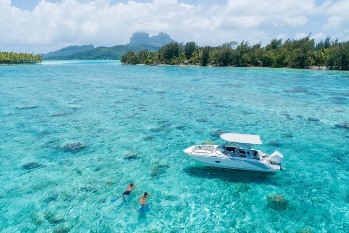 a blue and white boat sitting next to a body of water