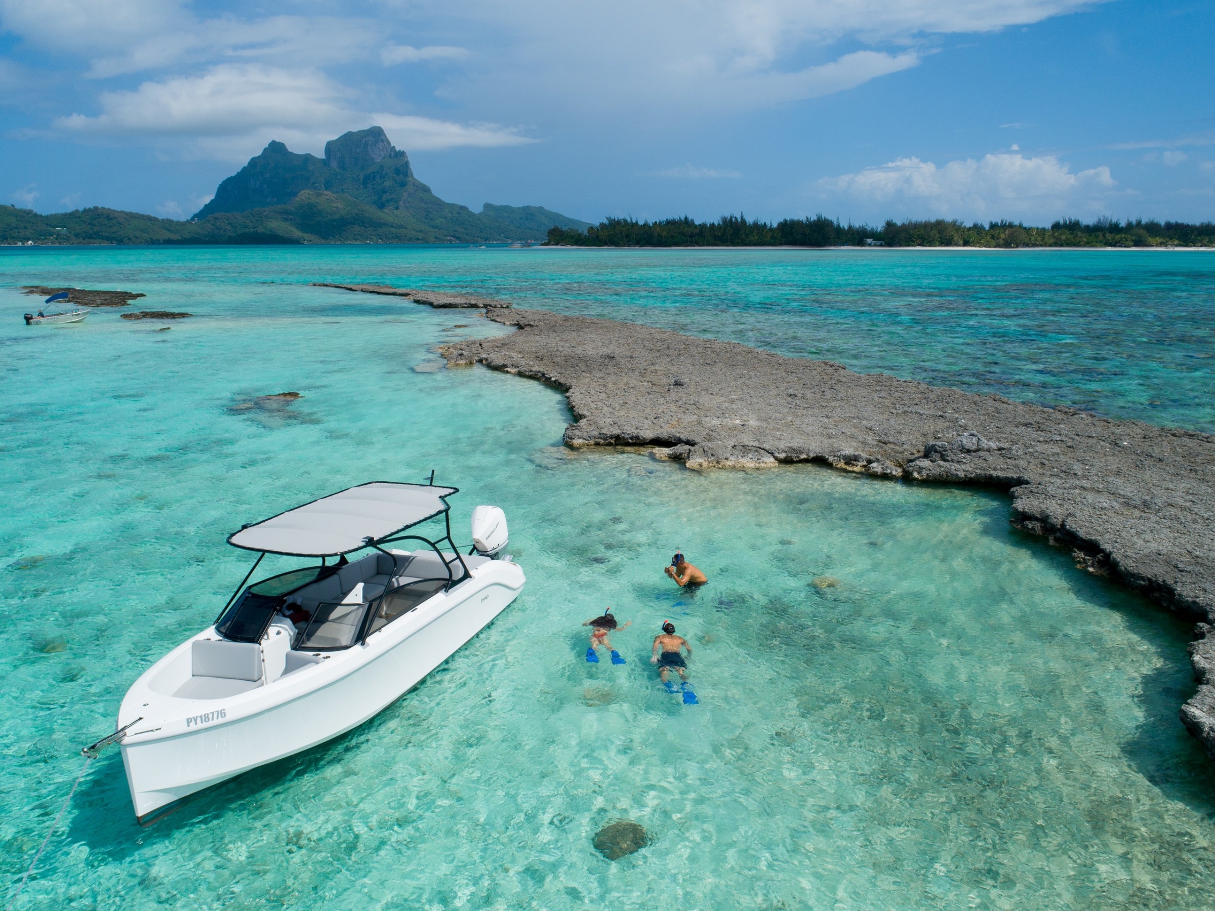 a group of people swimming in a body of water with Bora Bora in the background