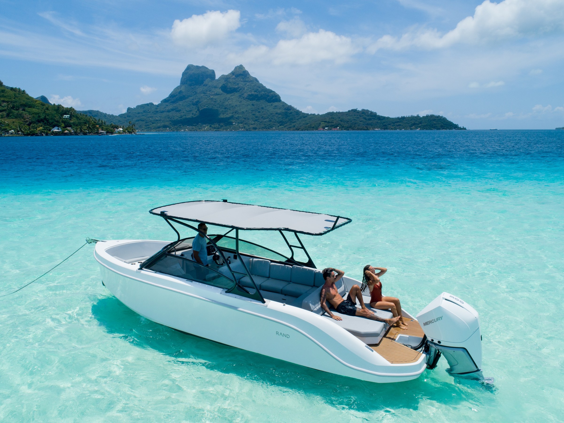 a blue and white boat sitting next to a body of water with Bora Bora in the background
